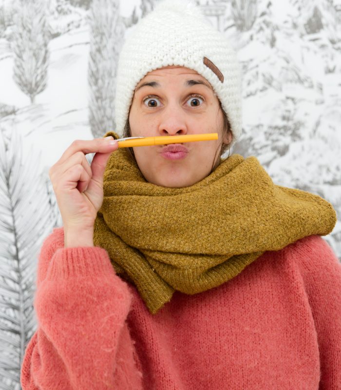 photographie rigolote de heloise godde illustratrice lifestyle travel avec un bonnet et un stylo comme moustache